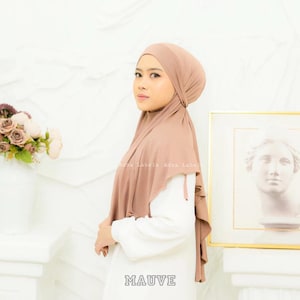 May include: Mauve colored jersey hijab with a gathered design. The hijab is worn by a person with a white shirt.