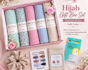 May include: A gift box set containing five rolled pashmina hijabs in solid and floral patterns, a velvet scrunchie, a box of eight hijab pins, a pair of magnetic hijab pins, and a package of hijab dress tape, all branded with Adha Labels.
