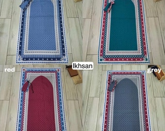 May include: Four prayer mats in blue, green, red, and gray, each with a matching small pouch. The mats feature a central arched design and a patterned border. The word "Ikhsan" is printed on the image.