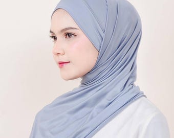 May include: A light blue jersey hijab with a smooth, silky texture. The hijab is draped over the head and neck, creating a simple and elegant look.