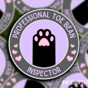 Peut inclure: Un autocollant rond violet et gris avec le texte "Professional Toe Bean Inspector" et une empreinte de patte noire avec des coussinets roses. L'autocollant a un motif de cœur rose autour de l'empreinte de patte.
