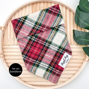 May include: Red and white plaid tie-on bandana with a green and yellow plaid pattern. The bandana has a white label with the text "Hazel Pup Designs".