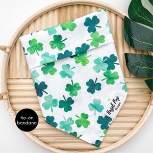 May include: White tie-on bandana with a green shamrock pattern. The bandana has the text "Hazel Pup Designs" in black.
