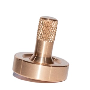May include: A gold-colored metal spinning top with a knurled top and a smooth, rounded base.
