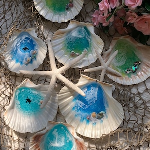 Pode incluir: Seis pratos de concha para joias com resina azul, verde e branca. Cada prato tem uma pequena tartaruga e glitter iridescente.