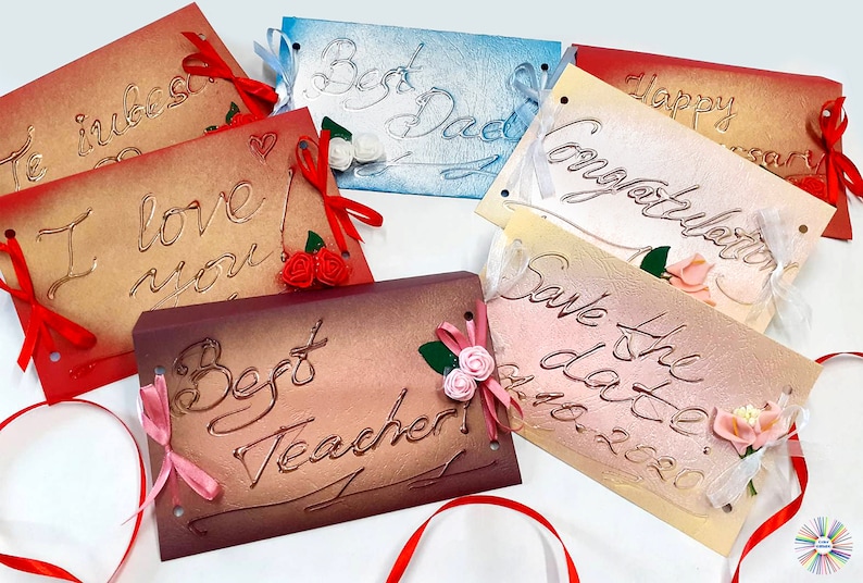 May include: Six handmade cards with different messages and embellishments. The cards are made of textured paper and have a vintage look. The messages include "I love you", "Best Dad", "Happy Anniversary", "Congratulations", "Save the Date", and "Best Teacher".