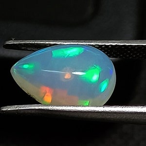 May include: A teardrop-shaped opal gemstone with a white body and iridescent green and orange flashes.