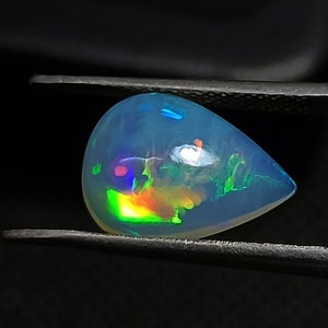 May include: A teardrop-shaped opal gemstone with a blue, green, and orange iridescent sheen.