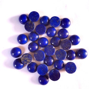 Könnte beinhalten: Eine Sammlung von 25 runden, blauen Lapislazuli-Cabochons. Die Cabochons sind glatt und poliert, in einem tiefen Blau mit goldenen Flecken.