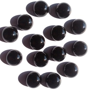 May include: A collection of 14 black glass spheres, each with a smooth, reflective surface. The spheres are arranged in a circular pattern on a white background.