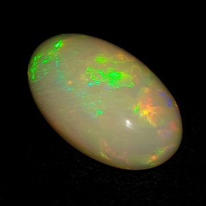 May include: A white oval opal gemstone with green and orange iridescence.