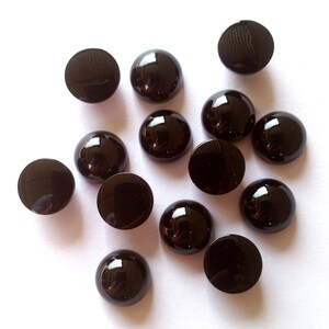 May include: A collection of 14 black round cabochon gems. The gems are smooth and shiny, with a slightly domed shape.