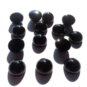 May include: A collection of 13 black gemstone cabochons, each with a smooth, polished surface. The cabochons are arranged in a random pattern on a white background.