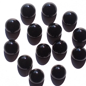 May include: A collection of 13 black glass marbles, each with a smooth, shiny surface.