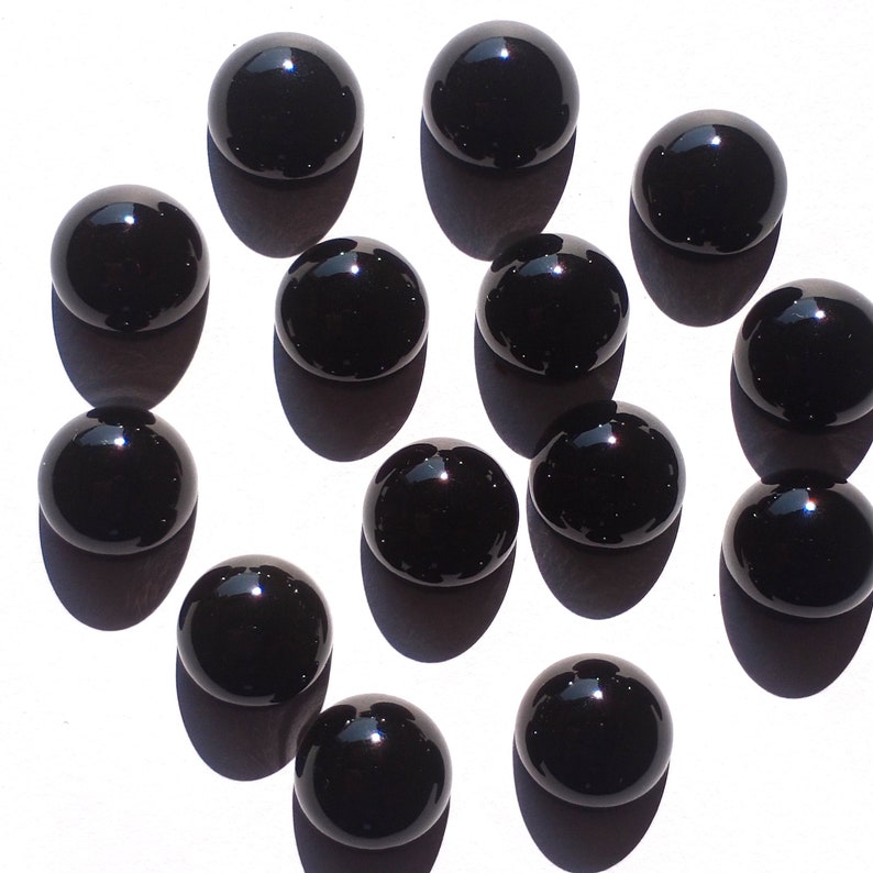 May include: A collection of 13 black glass marbles, each with a smooth, shiny surface.