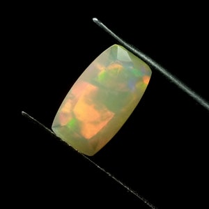 Könnte beinhalten: Ein hellgrüner Opal-Edelstein mit rechteckiger Form und einer glatten, polierten Oberfläche. Der Edelstein hat einen leichten irisierenden Schimmer.