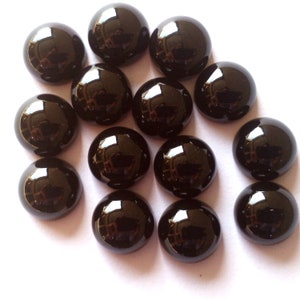 May include: A collection of 14 black cabochon gemstones, each with a smooth, rounded surface and a high gloss finish.