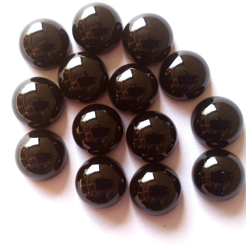 May include: A collection of 14 black cabochon gemstones, each with a smooth, rounded surface and a high gloss finish.