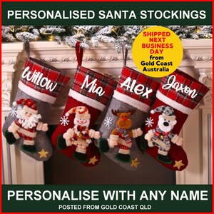 Può includere: Quattro calze di Natale personalizzate in tessuto a quadri rosso e bianco e feltro grigio. Le calze sono decorate con diversi personaggi, tra cui Babbo Natale, un pupazzo di neve, una renna e un orso polare. Le calze sono appese a un camino e ciascuna ha un nome ricamato sul davanti: Willow, Mia, Alex e Jaxon.