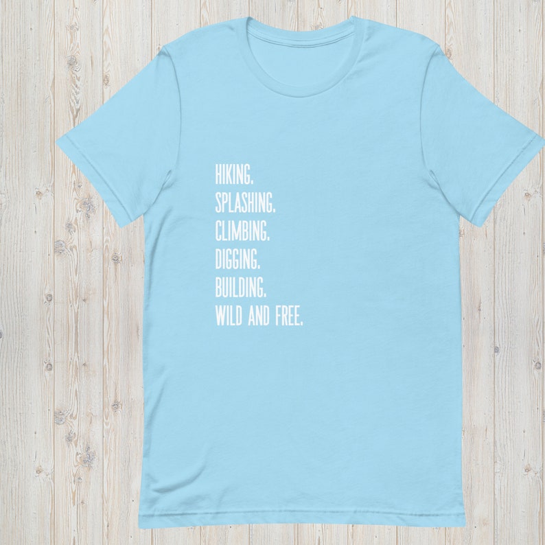 K&ouml;nnte beinhalten: Hellblaues T-Shirt mit dem Aufdruck "HIKING. SPLASHING. CLIMBING. DIGGING. BUILDING. WILD AND FREE." in Wei&szlig;.