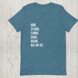 K&ouml;nnte beinhalten: Ein blaues T-Shirt mit dem Text "HIKING. SPLASHING. CLIMBING. DIGGING. BUILDING. WILD AND FREE." in wei&szlig; auf der Vorderseite.