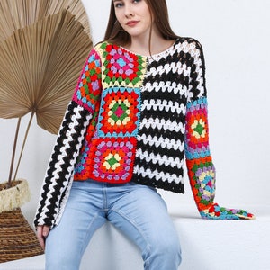 May include: A colorful crochet sweater with a black and white striped pattern. The sweater has a loose fit and long sleeves.