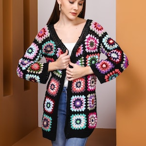 May include: A black crochet cardigan with a colourful geometric pattern. The cardigan has a V-neck and long sleeves.