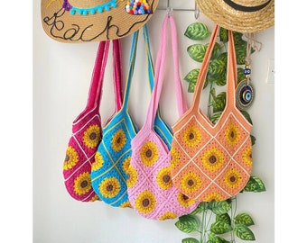 May include: Four crocheted bags with sunflower designs. The bags are pink, blue, green, and red. The bags are hanging from a rack.