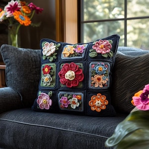 Puede incluir: Una almohada de ganchillo con un diseño floral en tonos de rosa, naranja, amarillo, azul y verde. La almohada está sobre un sofá gris oscuro con un reposabrazos de madera.