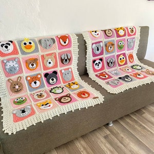Puede incluir: Dos mantas de crochet en un esquema de color rosa y blanco. Cada manta presenta una cara de animal diferente en cada cuadrado. Las mantas est&aacute;n en un sof&aacute; marr&oacute;n.
