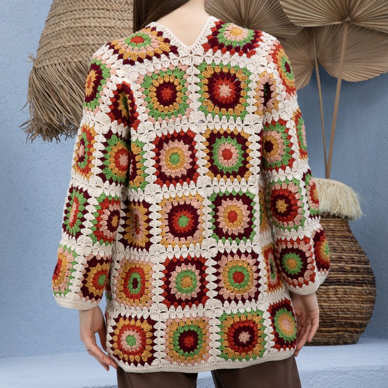Pu&ograve; includere: Un cardigan all'uncinetto con un motivo a quadrati della nonna in tonalit&agrave; crema, rosso, verde e arancione.