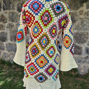 May include: A colorful crochet cardigan with a granny square pattern. The cardigan has long sleeves with bell bottoms and a ruffled hem.