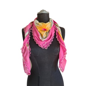 May include: A pink floral scarf with a lace trim. The scarf is draped over a black mannequin.
