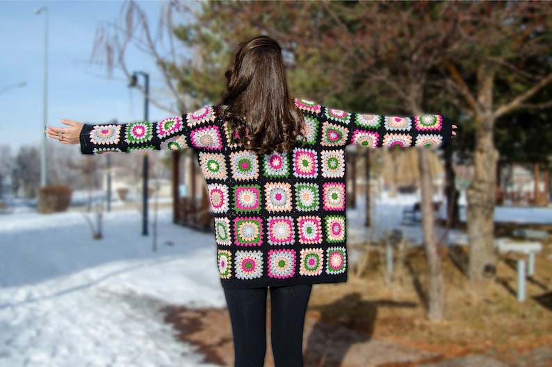 May include: A black crochet cardigan with colorful square patterns. The cardigan has long sleeves and a loose fit.