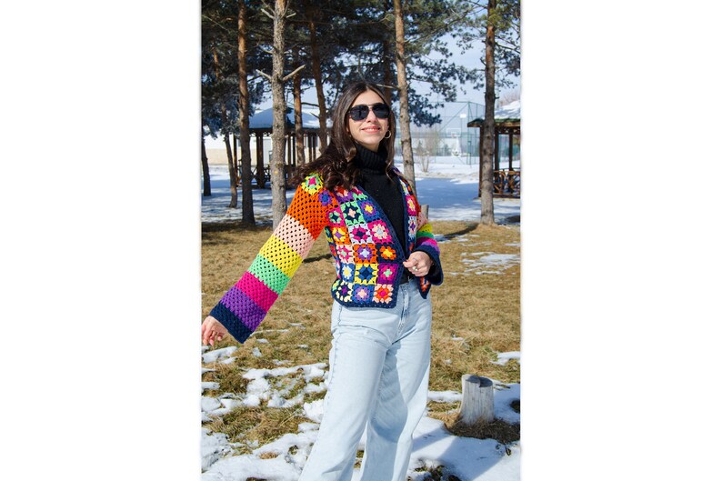Puede incluir: Una chaqueta de crochet colorida con un patr&oacute;n de rayas arco&iacute;ris en las mangas. La chaqueta est&aacute; hecha de una variedad de colores, incluyendo rojo, naranja, amarillo, verde, azul, morado y rosa.