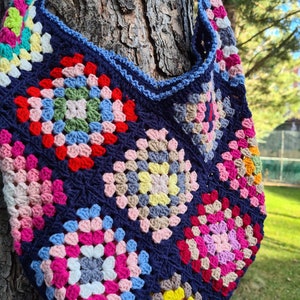 May include: A colorful crocheted tote bag with a blue background and a variety of granny squares in pink, red, yellow, green, and white.