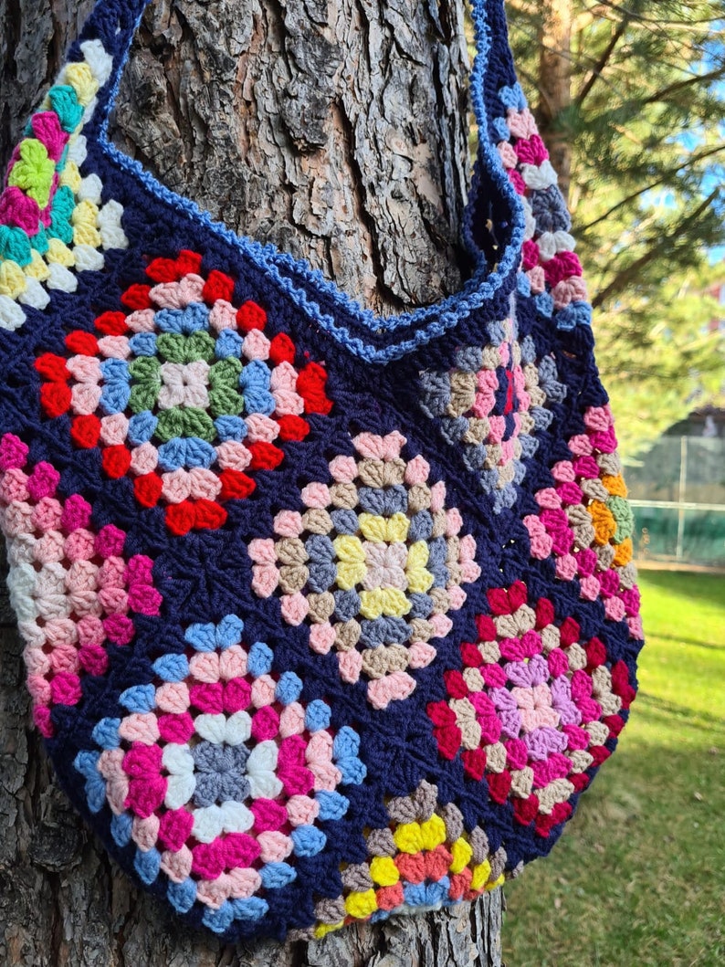 May include: A colorful crocheted tote bag with a blue background and a variety of granny squares in pink, red, yellow, green, and white.