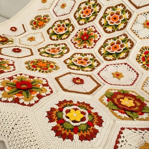 May include: A crocheted blanket with a white background and colorful floral motifs. The blanket is made up of hexagonal shapes with intricate designs in shades of orange, yellow, green, and red.