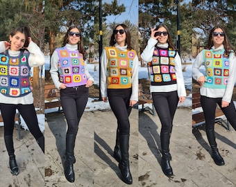 Può includere: Cinque donne indossano gilet di uncinetto di diversi colori con un motivo geometrico. Ogni gilet è fatto di quadrati colorati con una varietà di colori, tra cui rosa, blu, giallo, verde e arancione. Le donne indossano jeans neri e stivali neri.