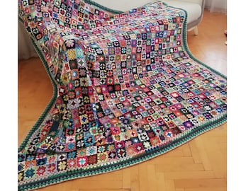 May include: A colorful crocheted throw blanket with a green border. The blanket is made of squares of different colors and patterns.