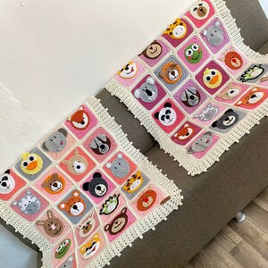 Puede incluir: Dos mantas de beb&eacute; de ganchillo con un borde blanco y cuadrados rosas y blancos con diferentes caras de animales.