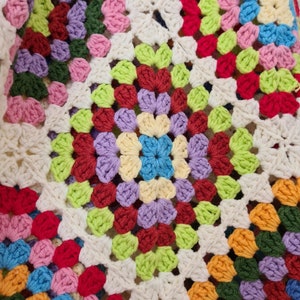 May include: A colorful crocheted blanket with a granny square pattern in shades of red, green, blue, yellow, and purple.