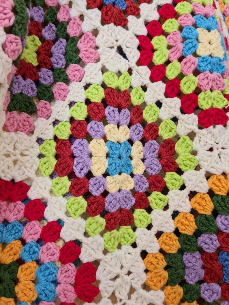 May include: A colorful crocheted blanket with a granny square pattern in shades of red, green, blue, yellow, and purple.