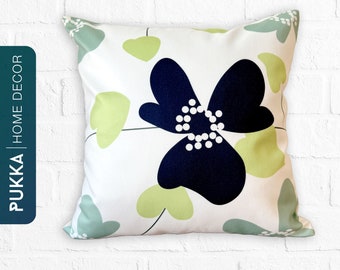 May include: A white throw pillow with a navy blue and green floral design. The pillow features a large navy blue flower with white dots in the center and green leaves.