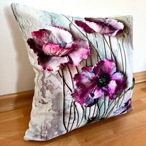 May include: A decorative throw pillow with a floral design featuring purple and pink poppies on a white background with a textured, watercolor-like effect.