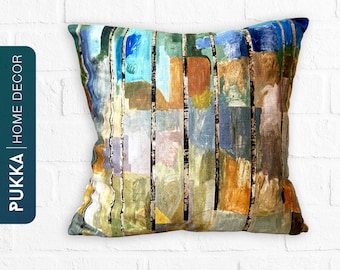 Puede incluir: Una almohada decorativa con un diseño abstracto colorido que presenta rayas verticales y formas geométricas en tonos de azul, verde, amarillo, naranja y marrón. La almohada está hecha de una tela suave y texturizada.