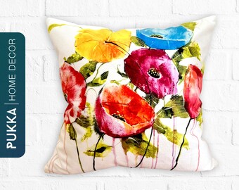 Peut inclure: Un oreiller blanc avec un motif aquarelle de coquelicots colorés. L'oreiller présente un mélange vibrant de teintes rouges, orange, jaunes, roses et bleues.