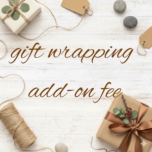May include: Image of gift-wrapped presents with brown ribbon and twine on a white wooden background. The text "gift wrapping add-on fee" is displayed in a brown script font. Decorative elements include small stones and gift tags.
