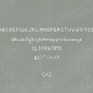 Op de afbeelding: Een handgeschreven alfabet in wit op een grijze achtergrond. Het alfabet bevat hoofdletters en kleine letters, cijfers en leestekens.