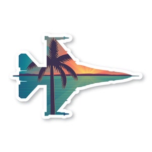 May include: A sticker featuring a silhouette of a fighter jet with a sunset and palm tree scene inside. The jet is blue and gray, the sunset is orange and pink, and the palm tree is black.